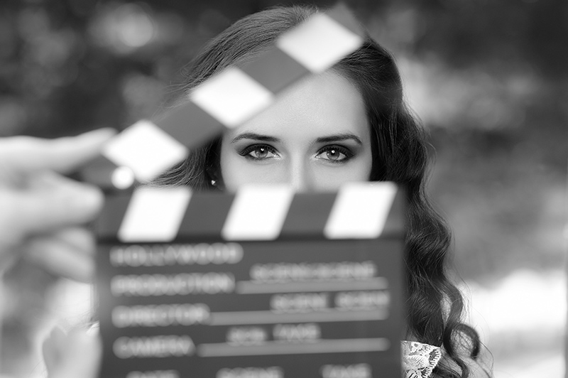 A woman is holding a movie clapper board