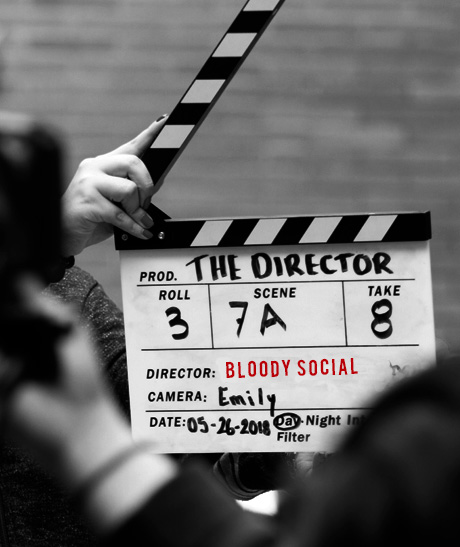 A person holding up a clapperboard in front of a camera.